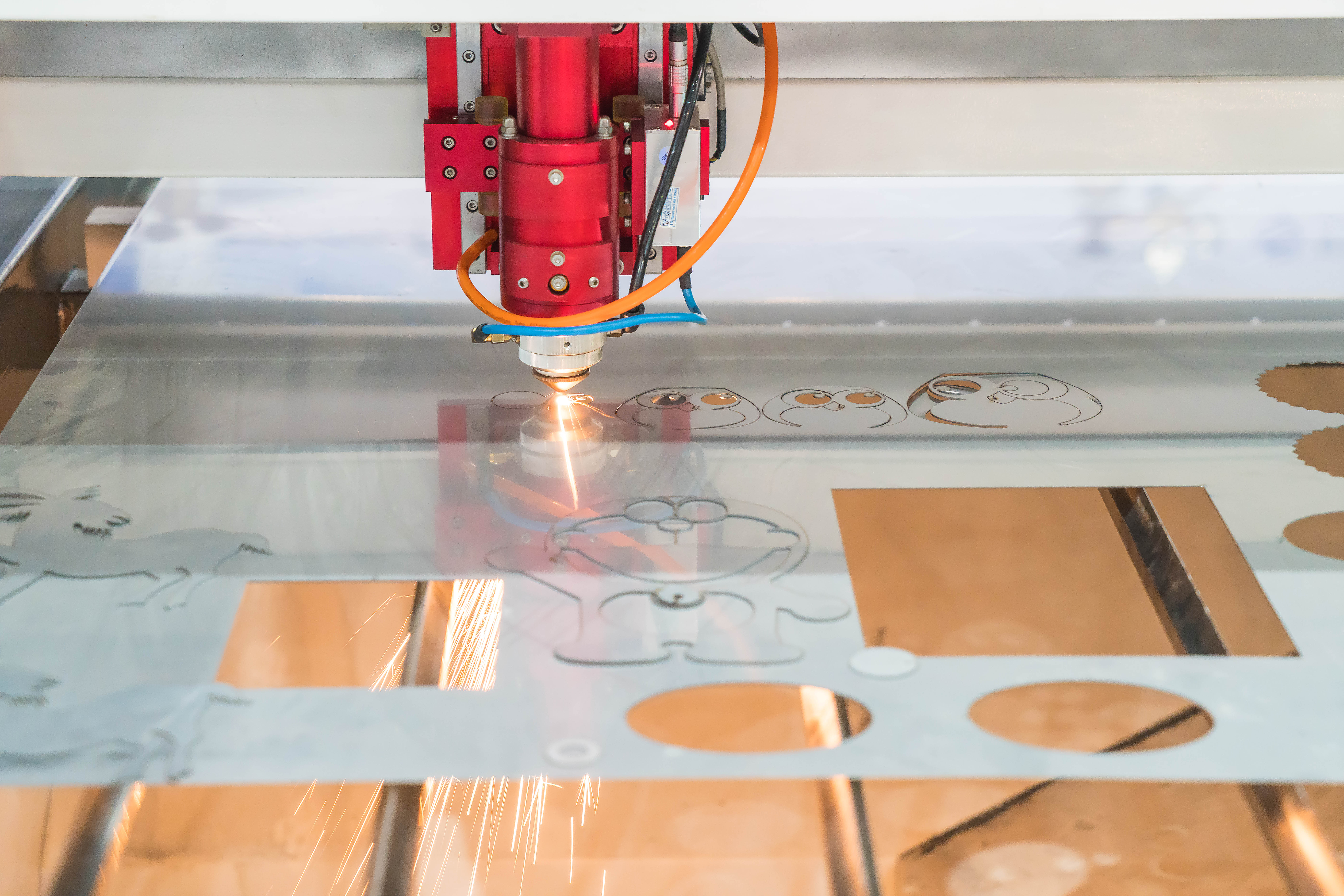 Laser cutting machine producing sparks on acrylic sheet